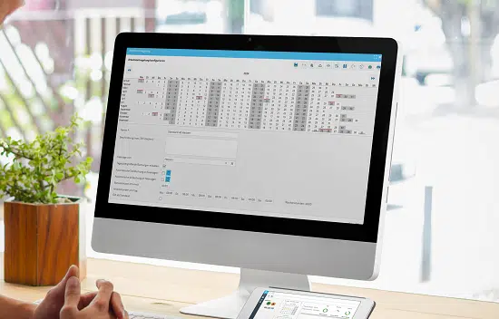 Arbeitsplatz mit Desktop-Monitor und geöffneter Zeiterfassungssoftware in der Einstellungen für Arbeitszeitmodelle definiert werden.