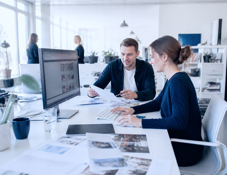 Zwei Mitarbeitende besprechen geschäftliche Unterlagen am Arbeitsplatz